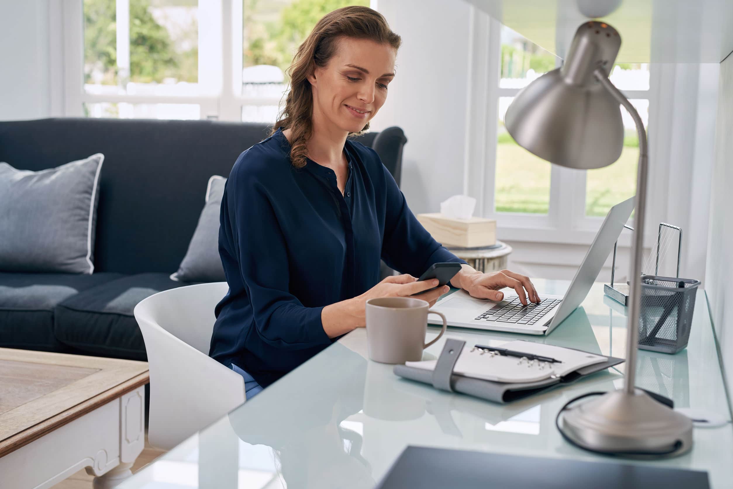 female home-based worker using her monile phone and laptop to earn