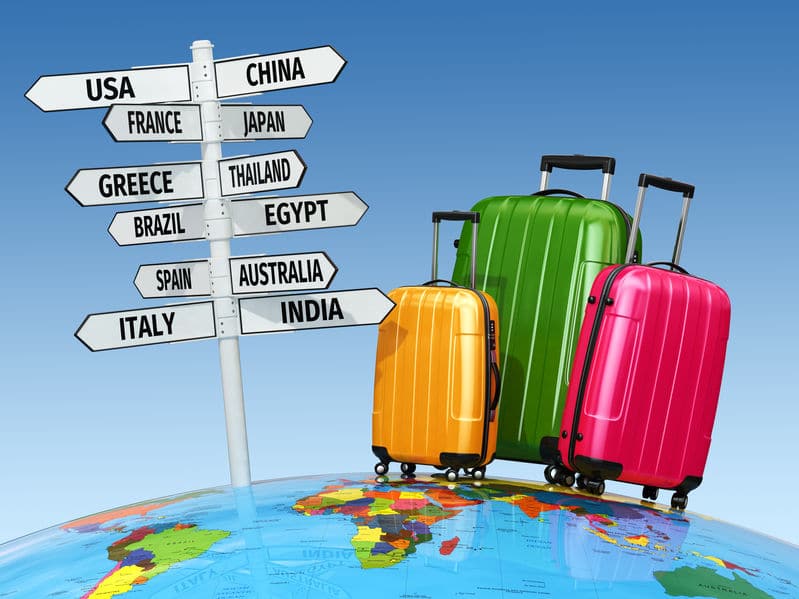 colored luggage beside a signpost of countries