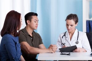 medical interpretion in action - doctor talking to asian couple about their medical test results